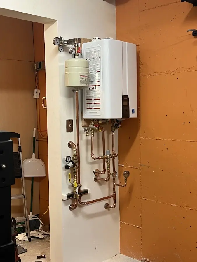 Plumbing technician inspecting water heater connections in Croghan